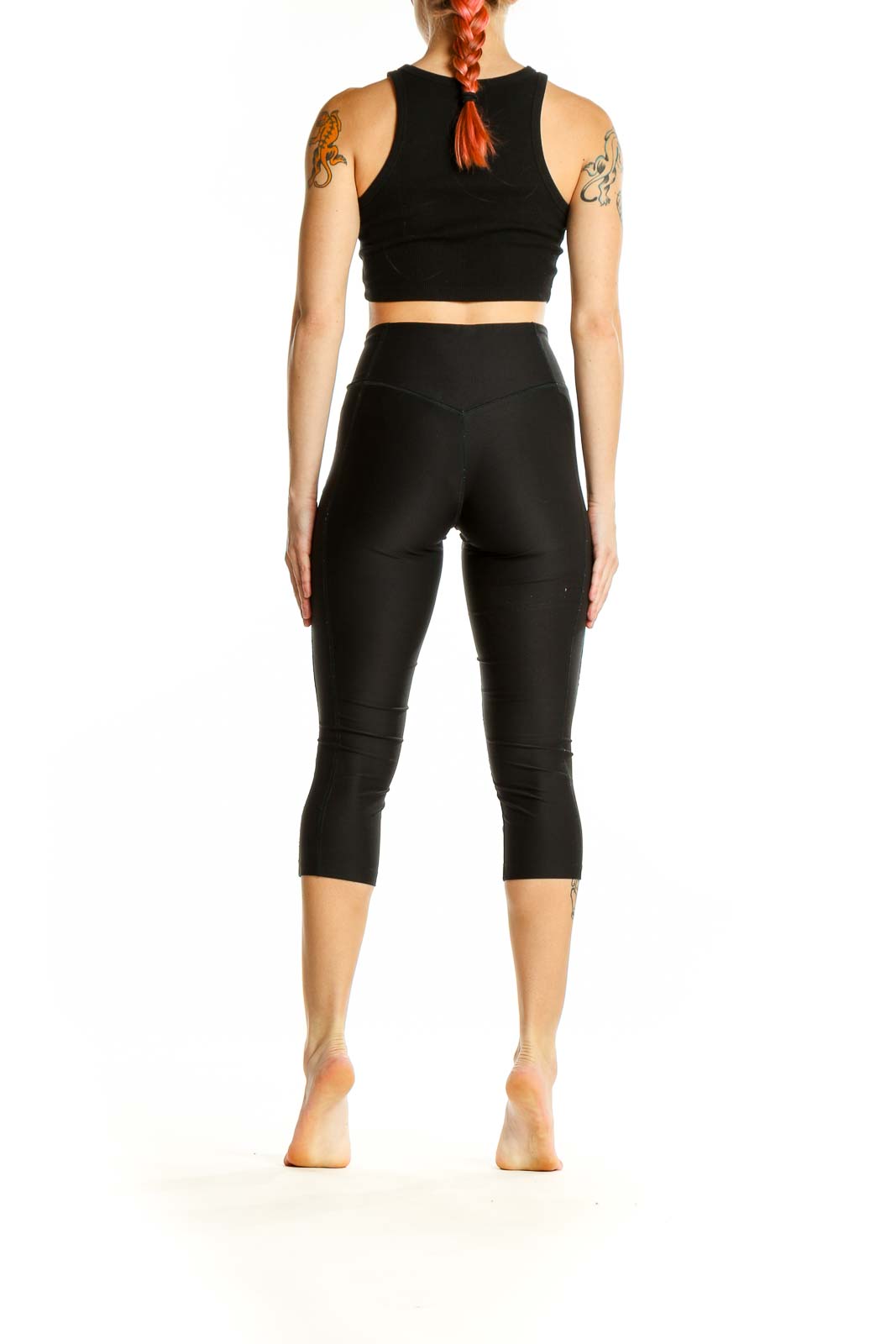 Side view of woman wearing black Nike capri leggings and crop top