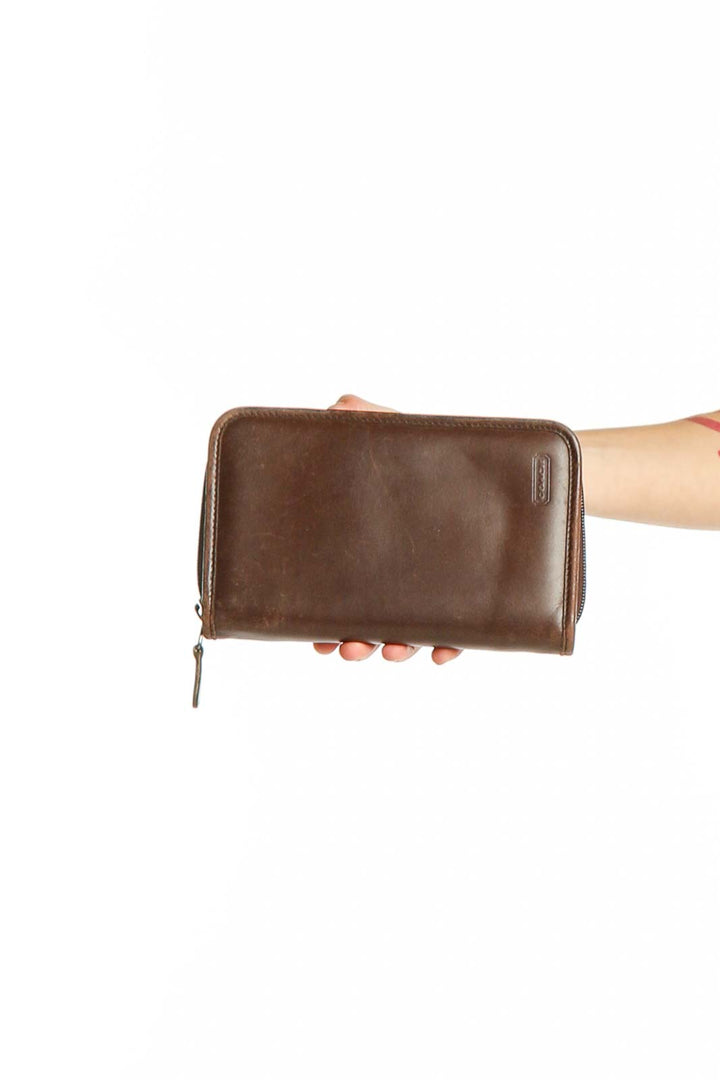 Front view of brown leather Coach zip-around wallet held in hand