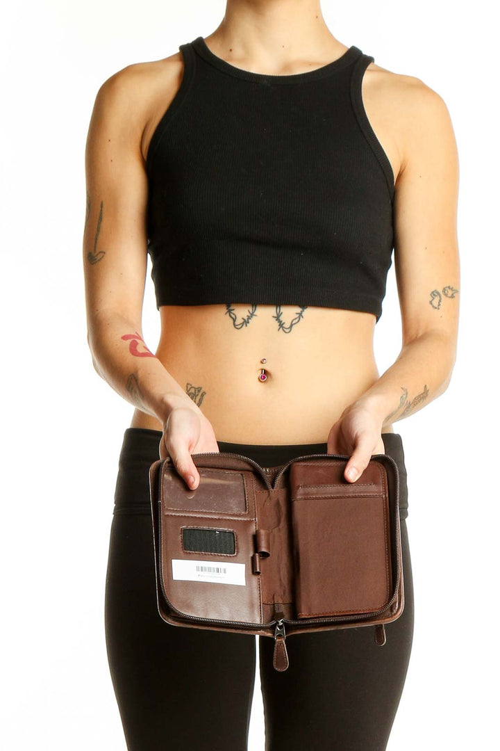 Person holding brown leather Coach zip-around wallet, showcasing its compact size