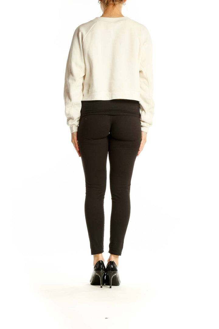 Side view of model wearing cream crop sweatshirt with black pants