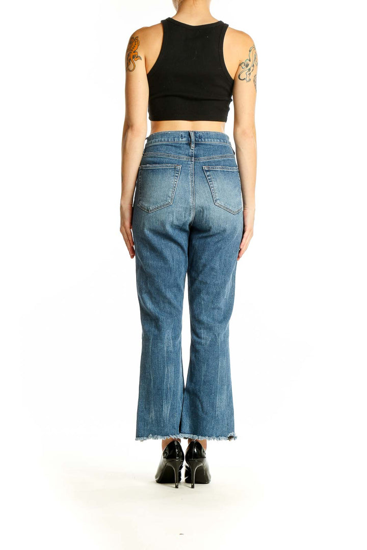 Back view of LOFT blue cropped flare jeans on model