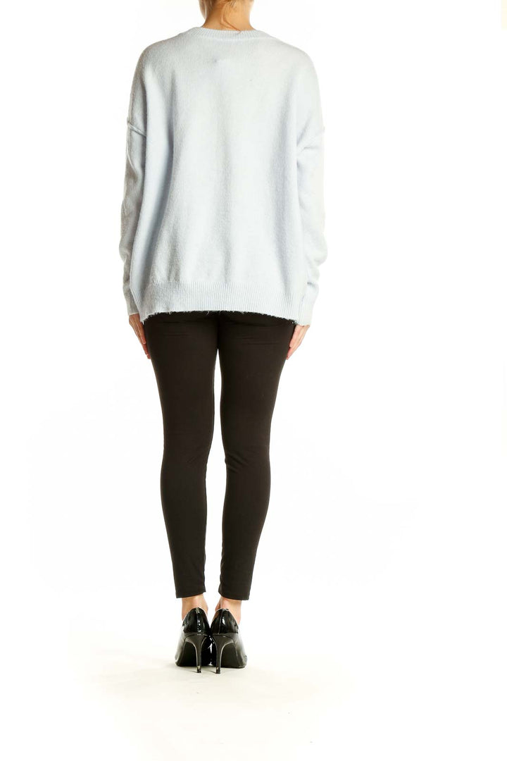 Side view of model wearing Vince Camuto light blue oversized knit sweater with black leggings