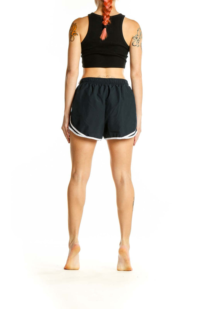 Side view of woman wearing black Nike running shorts and black crop top