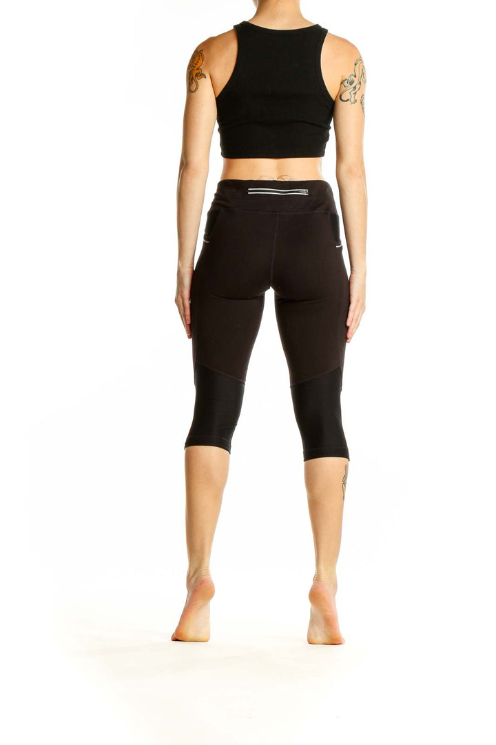 Side view of woman wearing black Athleta cropped leggings and crop top