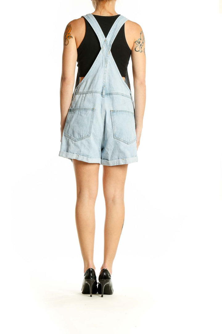 Side view of SilkRoll light blue denim short overalls showing adjustable straps and cuffed hem