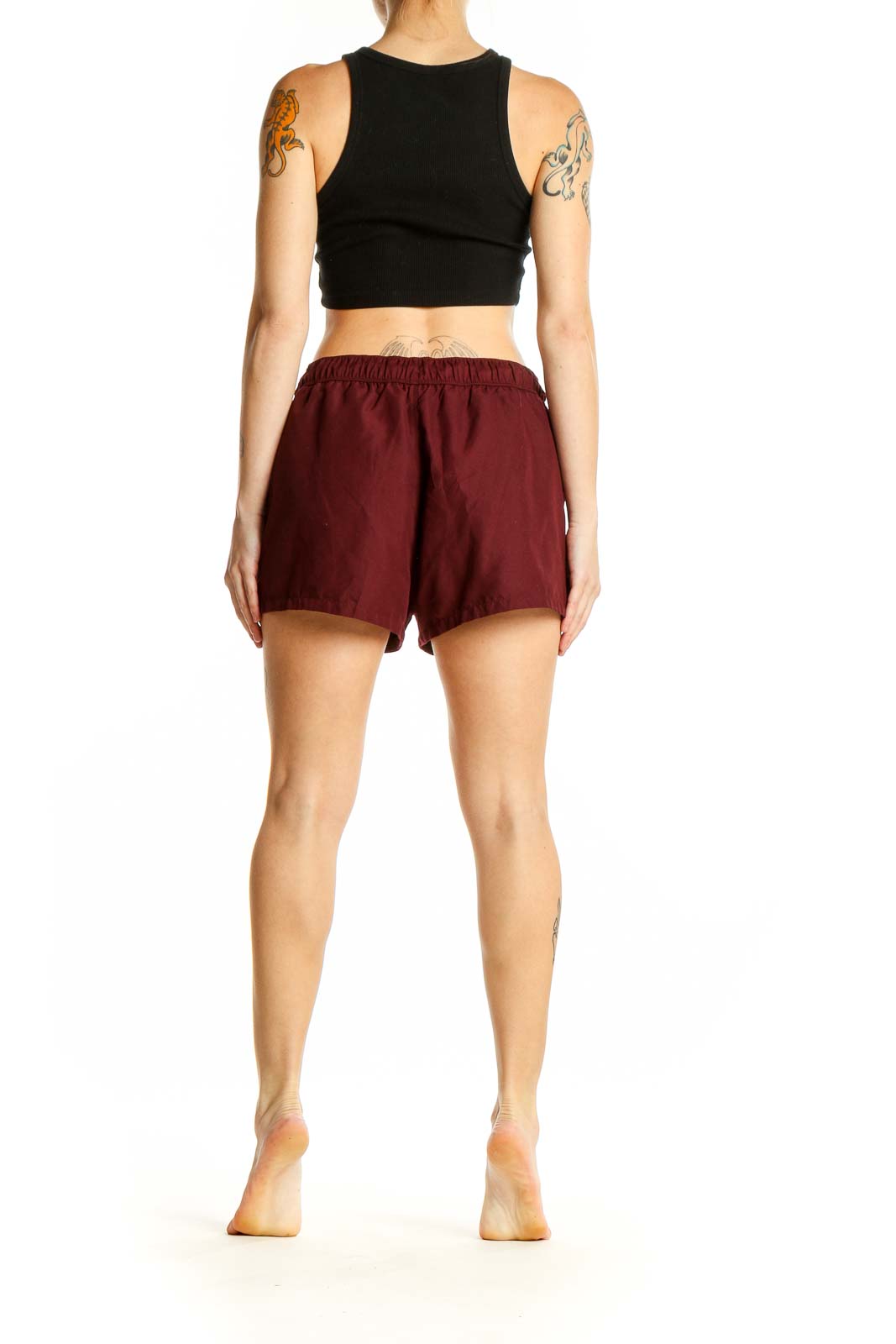 Side view of model wearing burgundy ASOS athletic shorts with black crop top