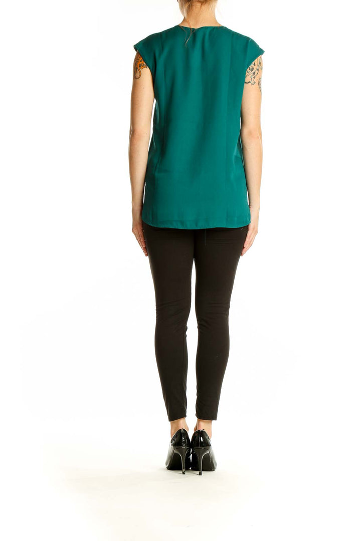 Side view of model wearing emerald green sleeveless V-neck blouse by J.Crew Mercantile with black pants