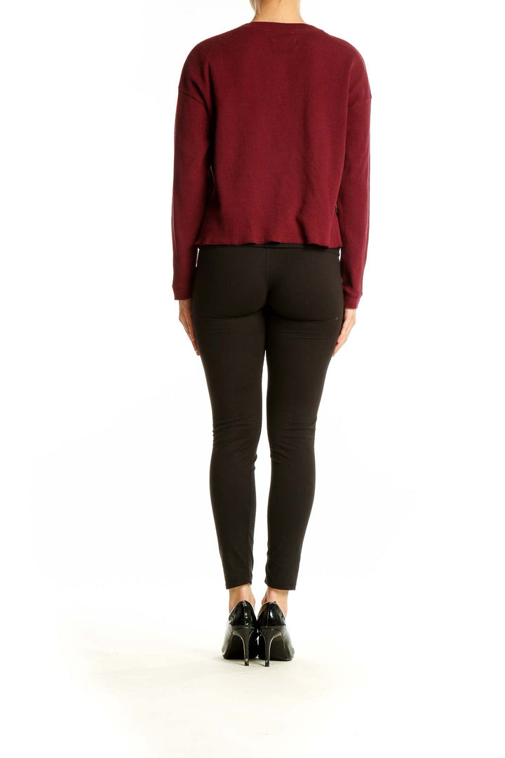 Back view of Everlane burgundy cotton henley knit top on model with black pants