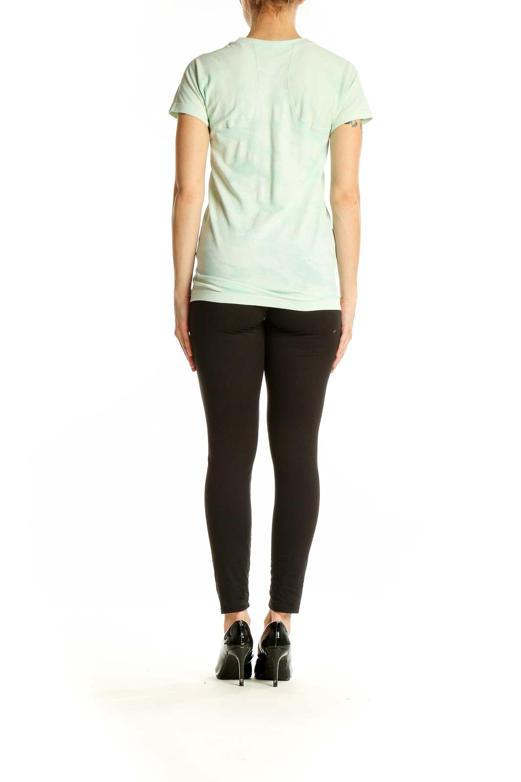 Side view of woman wearing mint green Athleta performance t-shirt with black pants