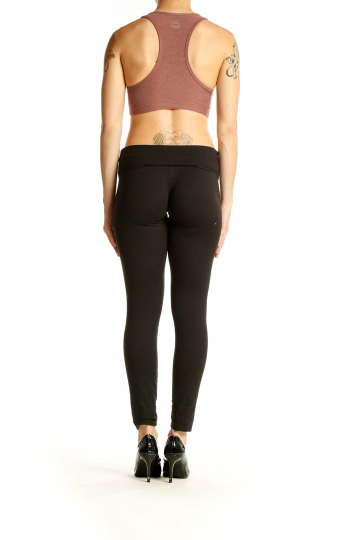 Side view of woman wearing mauve racerback sports bra and black leggings