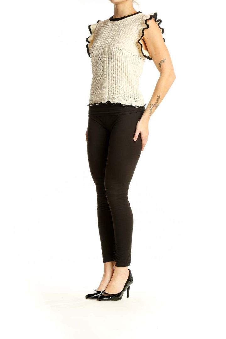 Front view of cream sleeveless knit top with ruffled armholes and mixed knit patterns