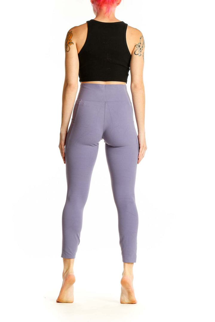 Side view of woman wearing lavender high-waisted REI COOP leggings with black crop top