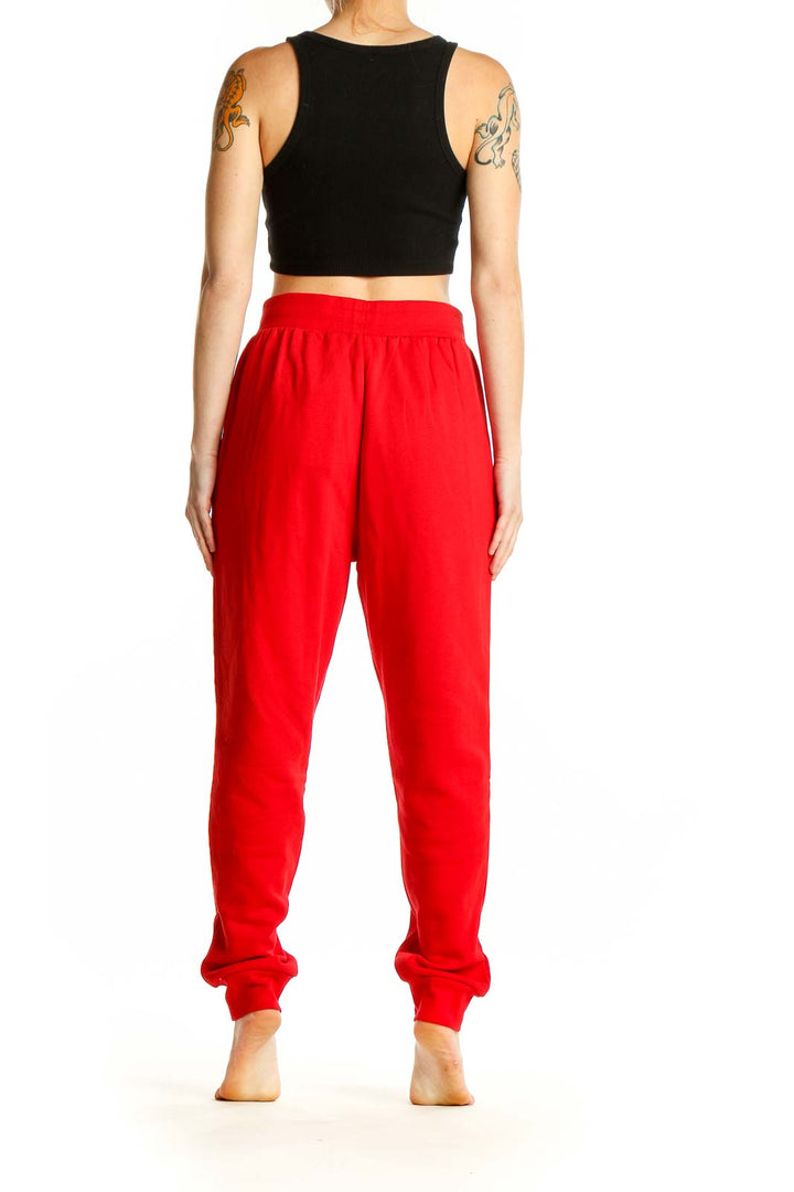 Side view of woman wearing red Adidas cotton jogger sweatpants with black crop top