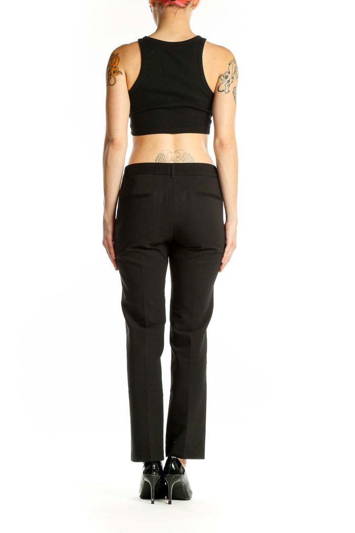 Side view of woman wearing AMANDA + CHELSEA black straight-leg trousers with black top