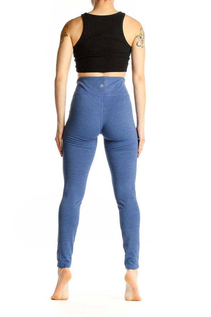 Side view of woman wearing blue Athleta high-waisted leggings with black crop top