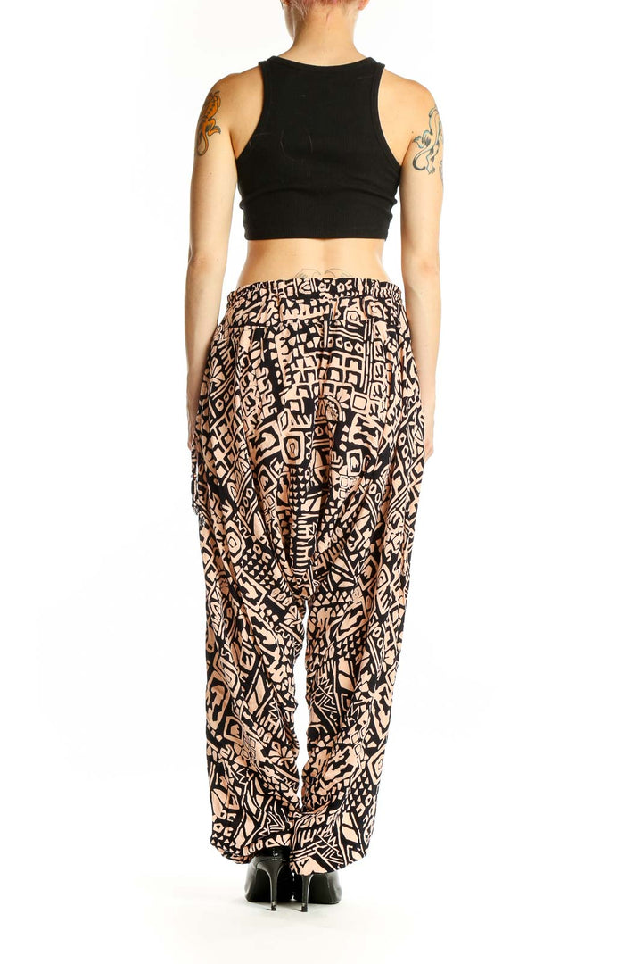 Side view of model wearing black and tan geometric print wide-leg pants by Buddha Pants with black crop top