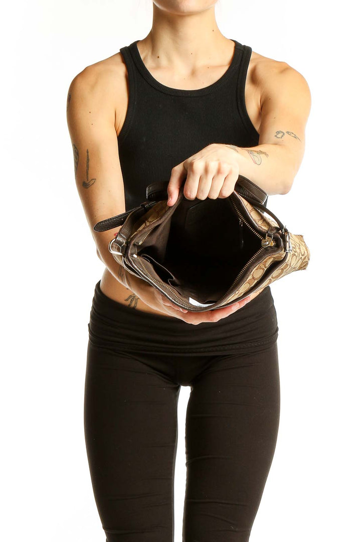 Model wearing tan Coach Signature Canvas Crossbody Bag with black outfit