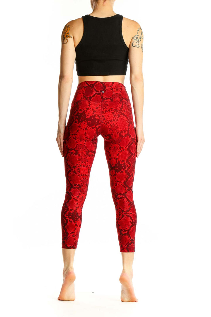 Side view of woman wearing red snake print Lululemon cropped leggings with black top