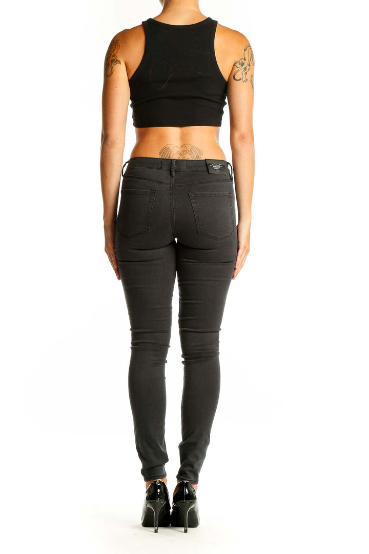 Side view of woman wearing black Bullhead skinny jeans with crop top
