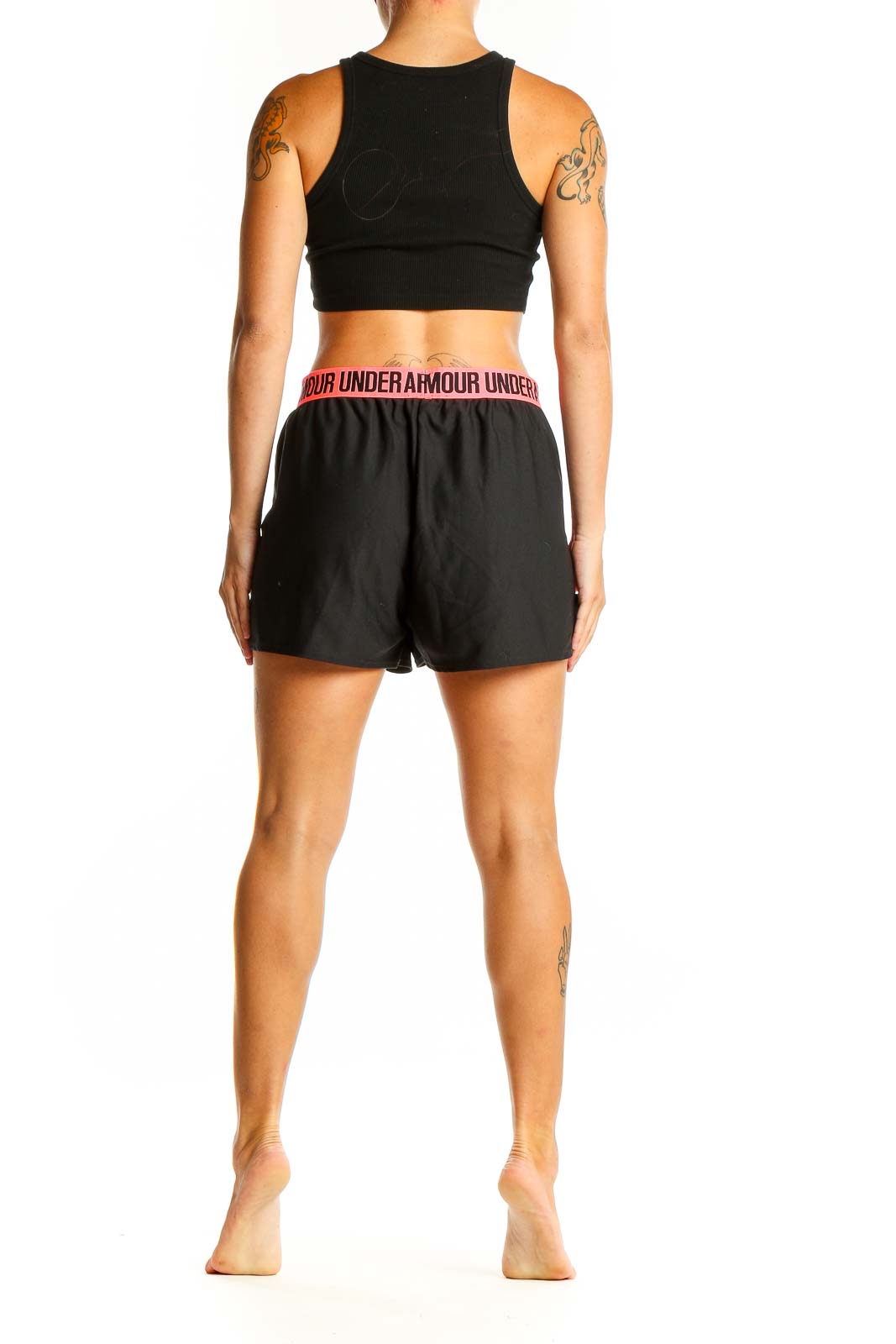 Side view of person wearing black Under Armour athletic shorts with pink accents