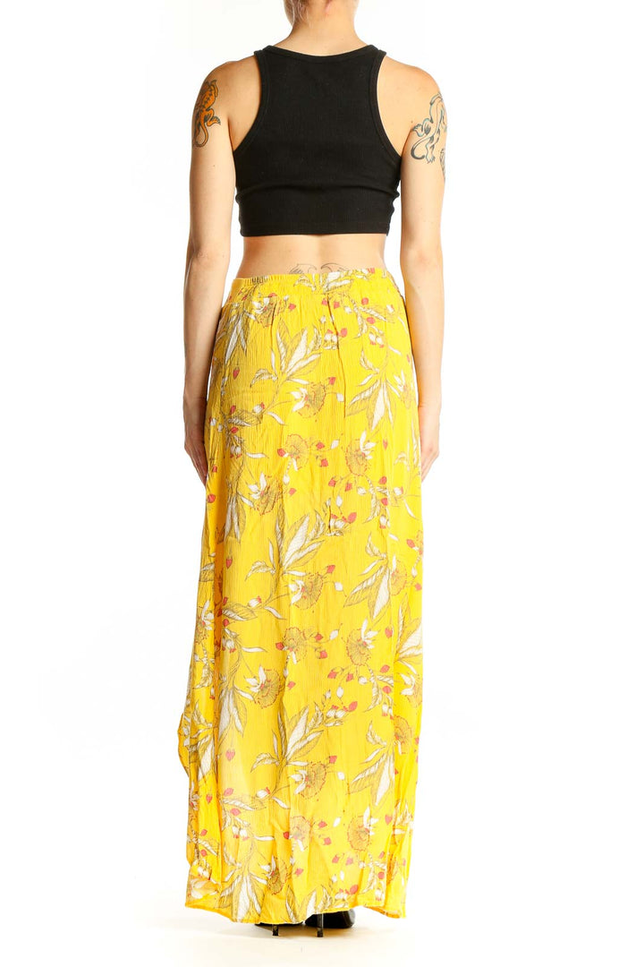 Side view of model wearing yellow floral maxi skirt with black crop top