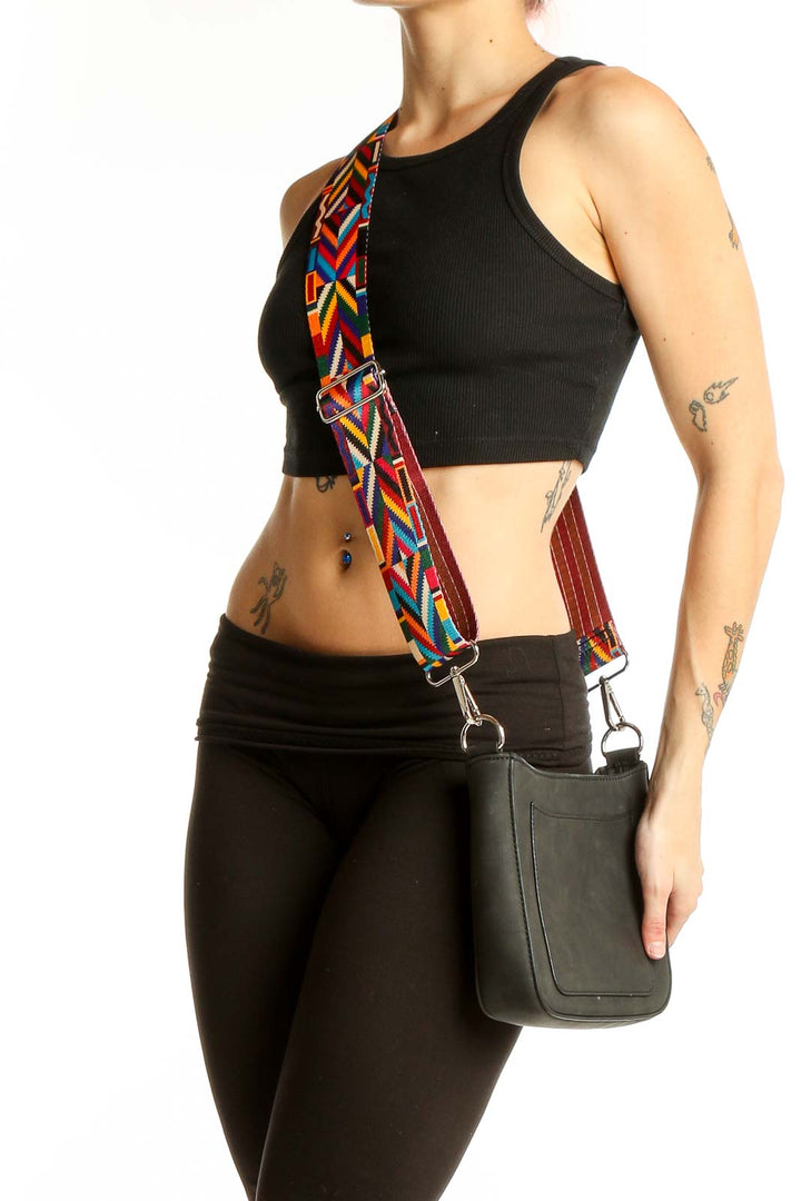 Front view of K.carroll black crossbody bag with colorful geometric strap