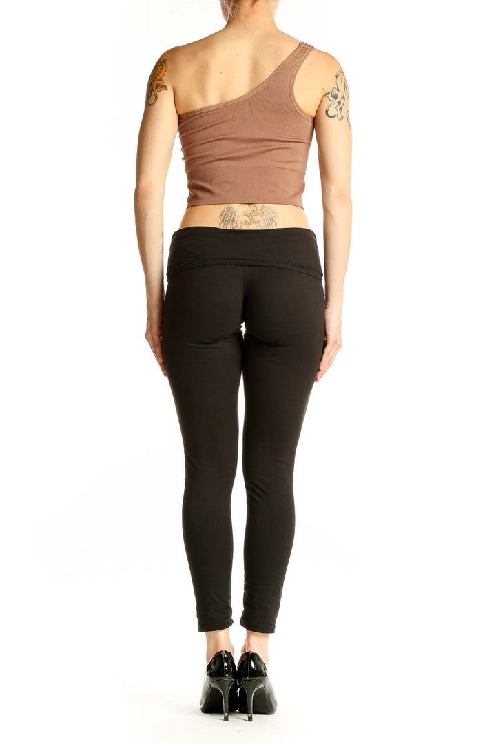 Side view of model wearing tan one-shoulder crop top with black leggings