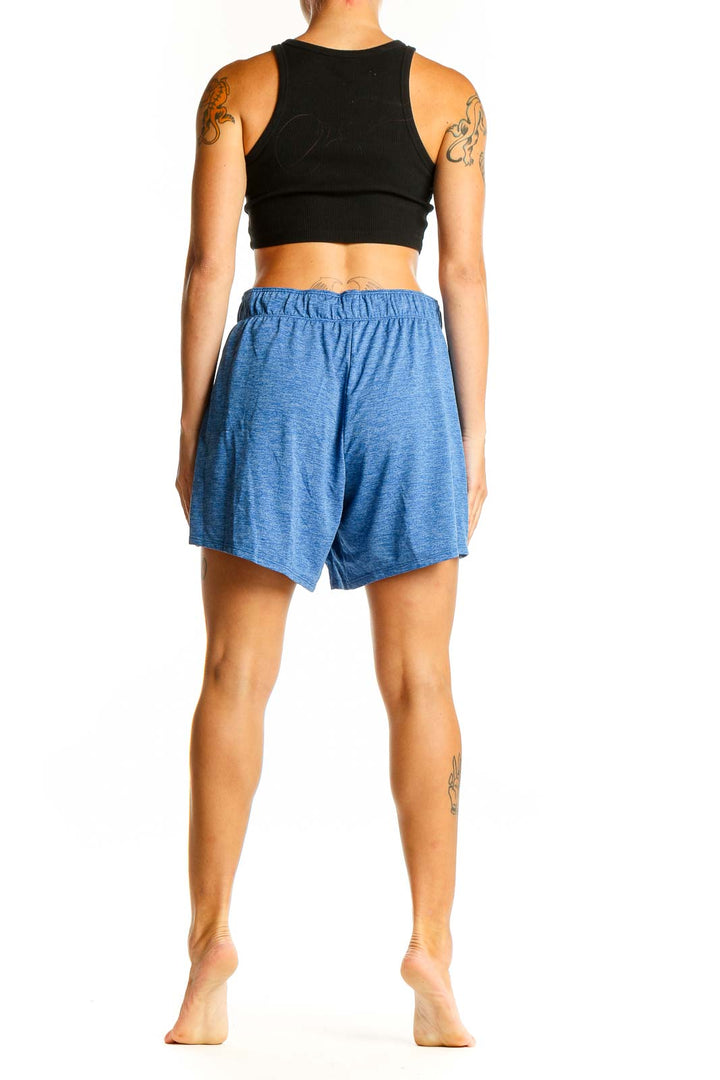 Side view of woman wearing Nike heathered blue athletic shorts and black crop top