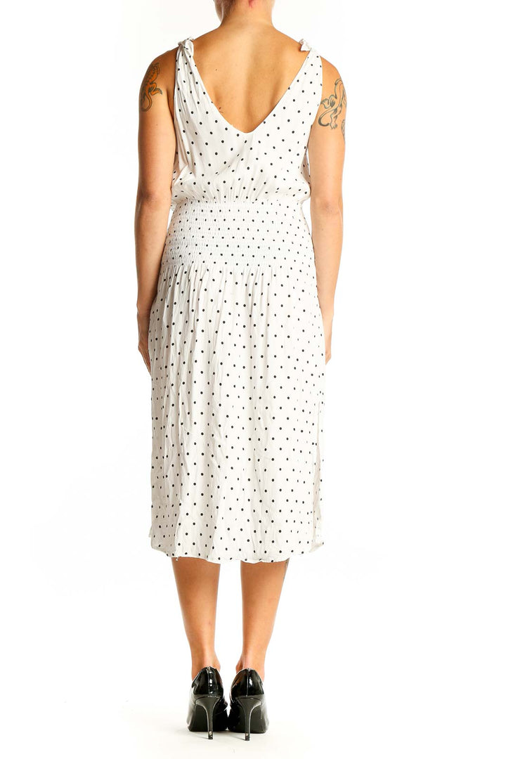 Side view of white polka dot midi dress showing smocked waist and flowy skirt