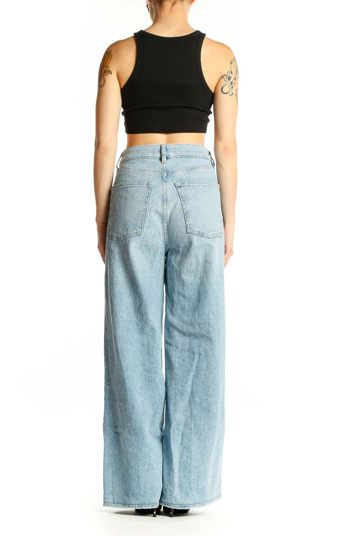 Side view of Warp Weft light blue wide-leg jeans on model with black crop top