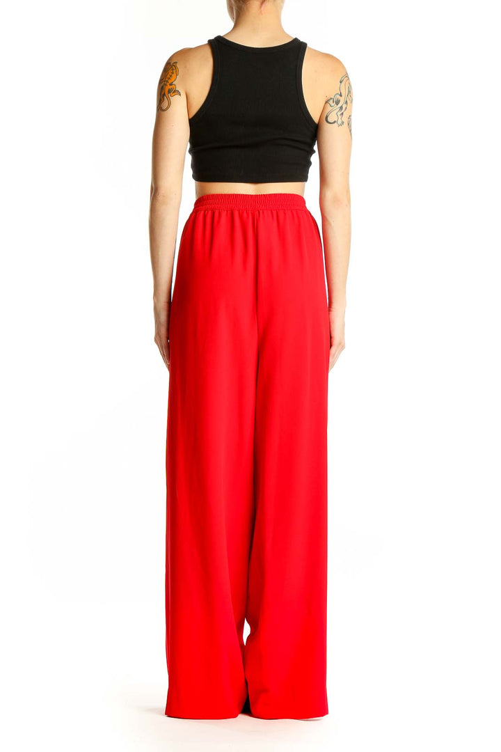 Side view of model wearing red DKNY wide-leg pants with black crop top