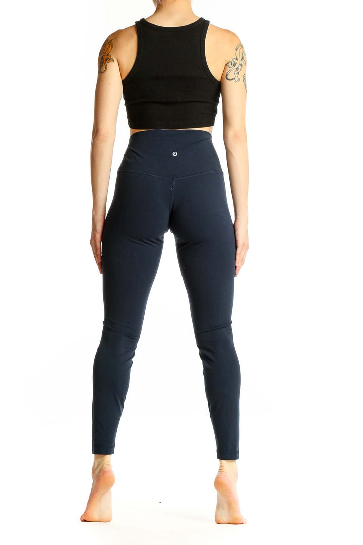 Side view of Lululemon navy high-waisted leggings on model with black crop top