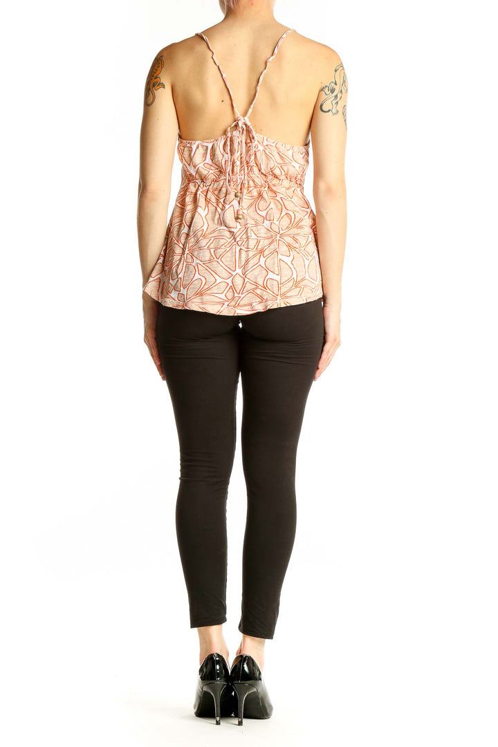 Side view of model wearing Roxy peach floral print cami top with black pants