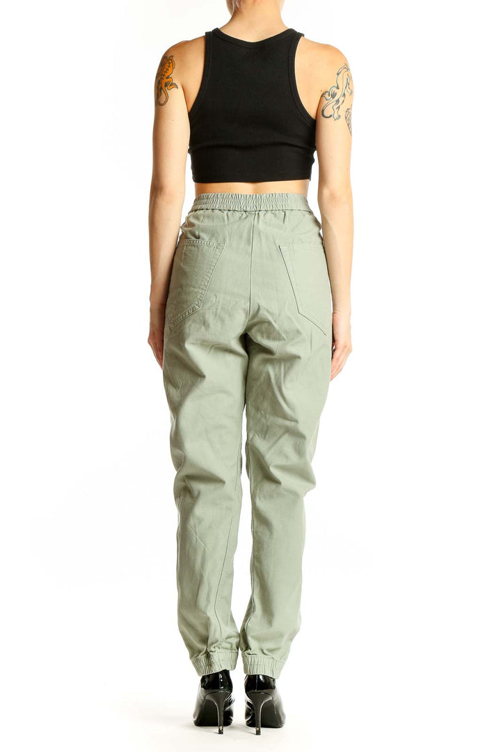 Side view of woman wearing Rag & Bone sage green cotton jogger pants with black crop top