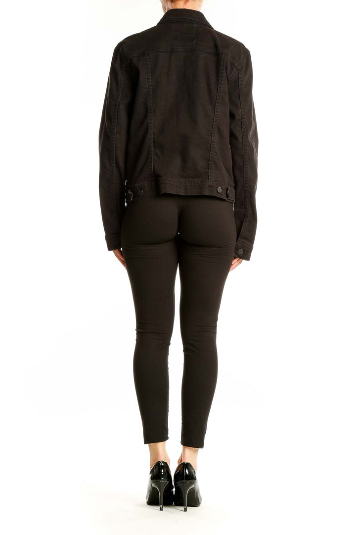 Back view of black Levi's denim jacket on model with black pants