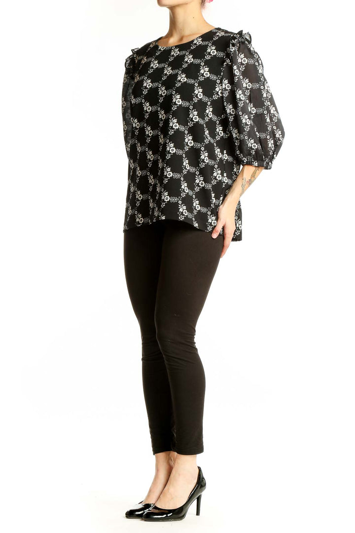 Front view of Ann Taylor black blouse with white floral print and puff sleeves