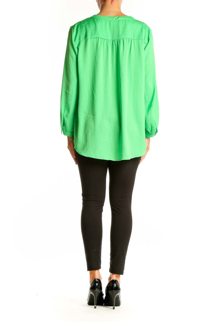 Side view of model wearing Vince Camuto green V-neck polyester blouse with black pants