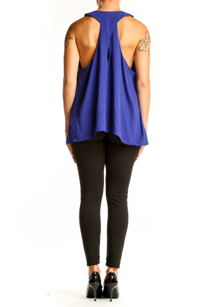 Side view of woman wearing royal blue V-neck sleeveless blouse from Banana Republic with black pants