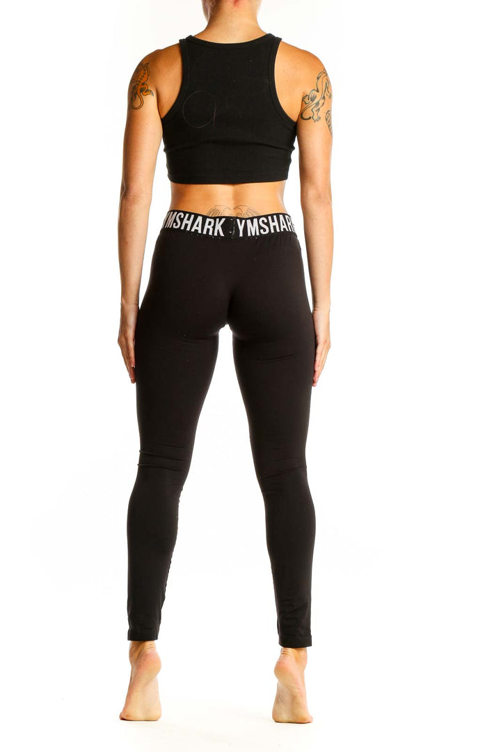 Side view of black Gymshark high-waisted leggings and crop top on female model