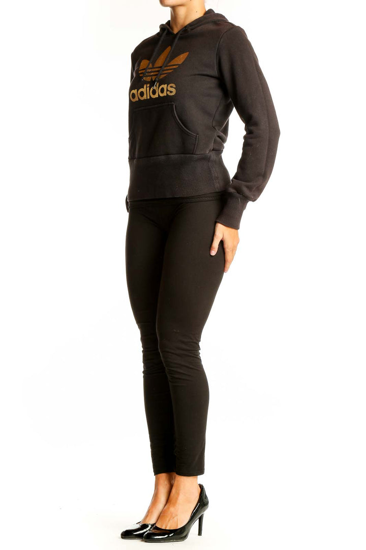 Front view of black Adidas hoodie with gold Trefoil logo