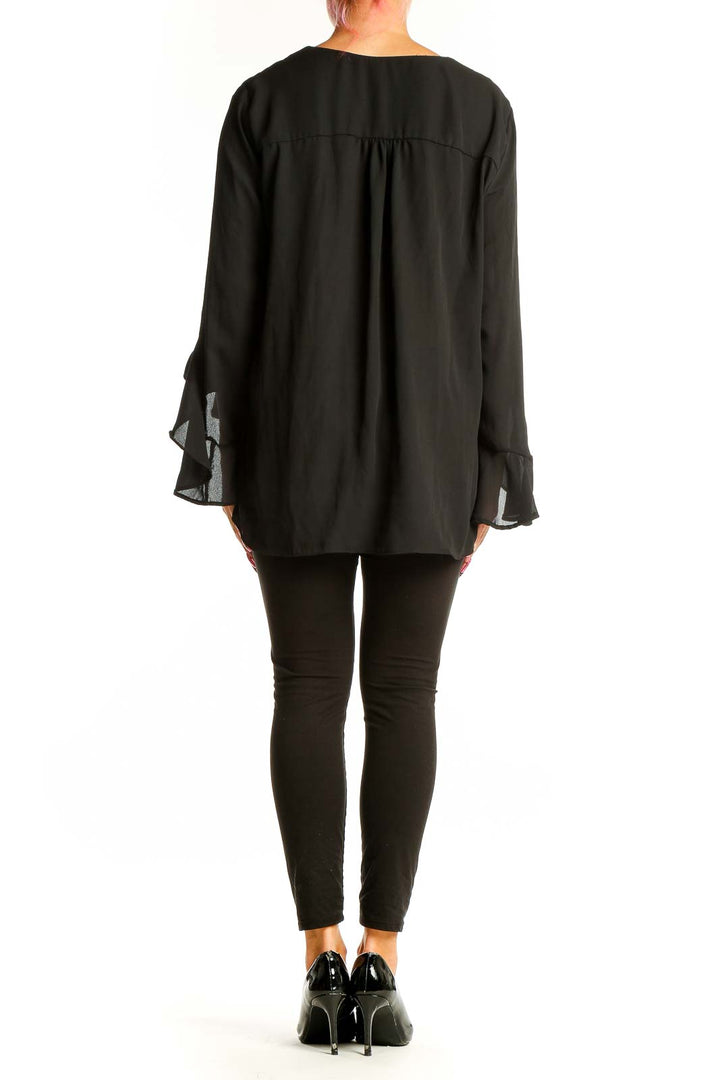 Side view of model wearing black Vince Camuto V-neck blouse with bell sleeves