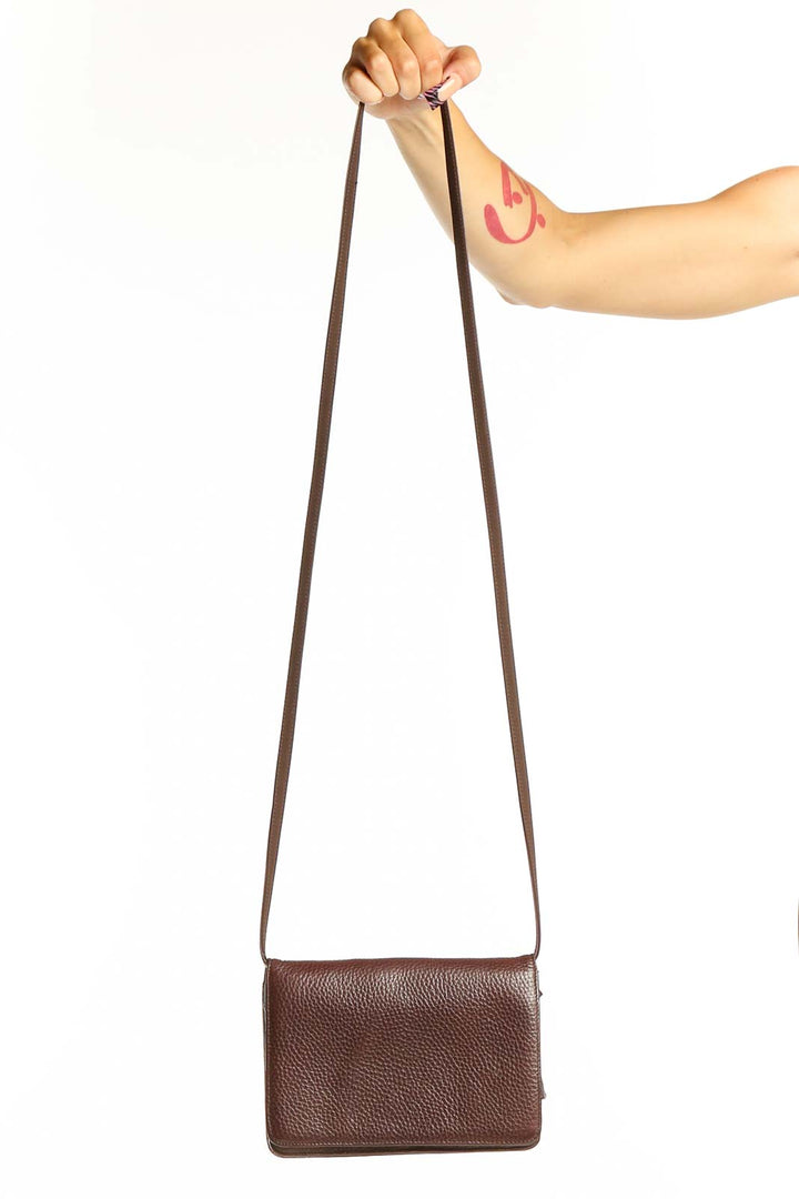 Front view of brown leather Classiques Entier crossbody bag held by model's hand