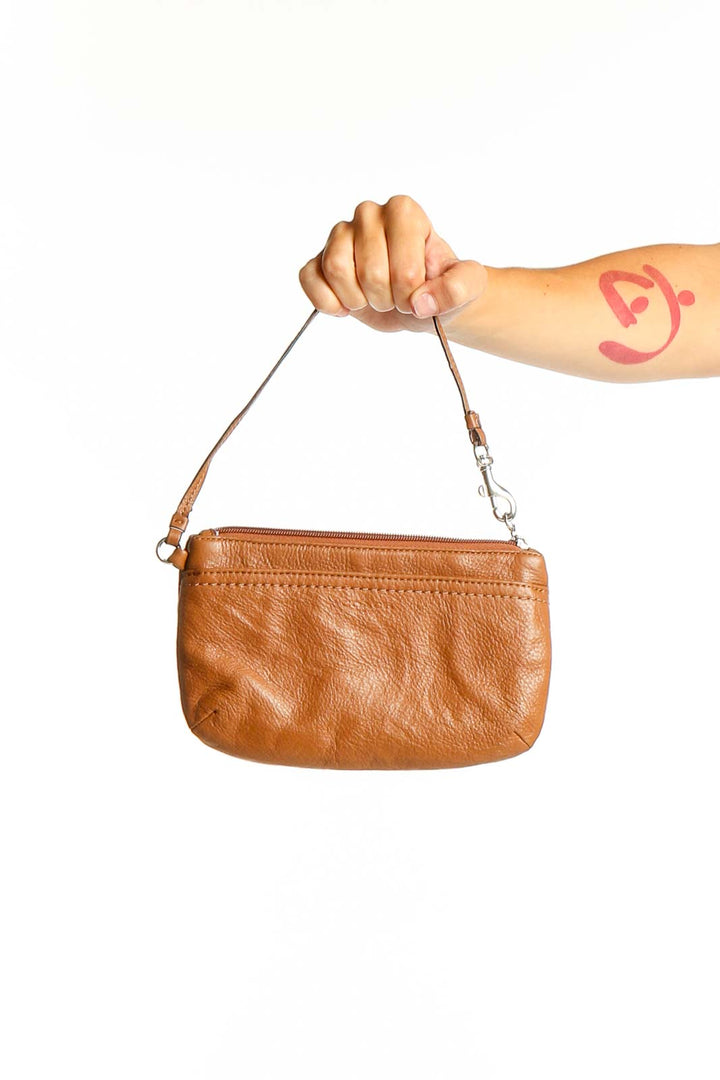 Front view of tan leather Coach wristlet clutch held by hand