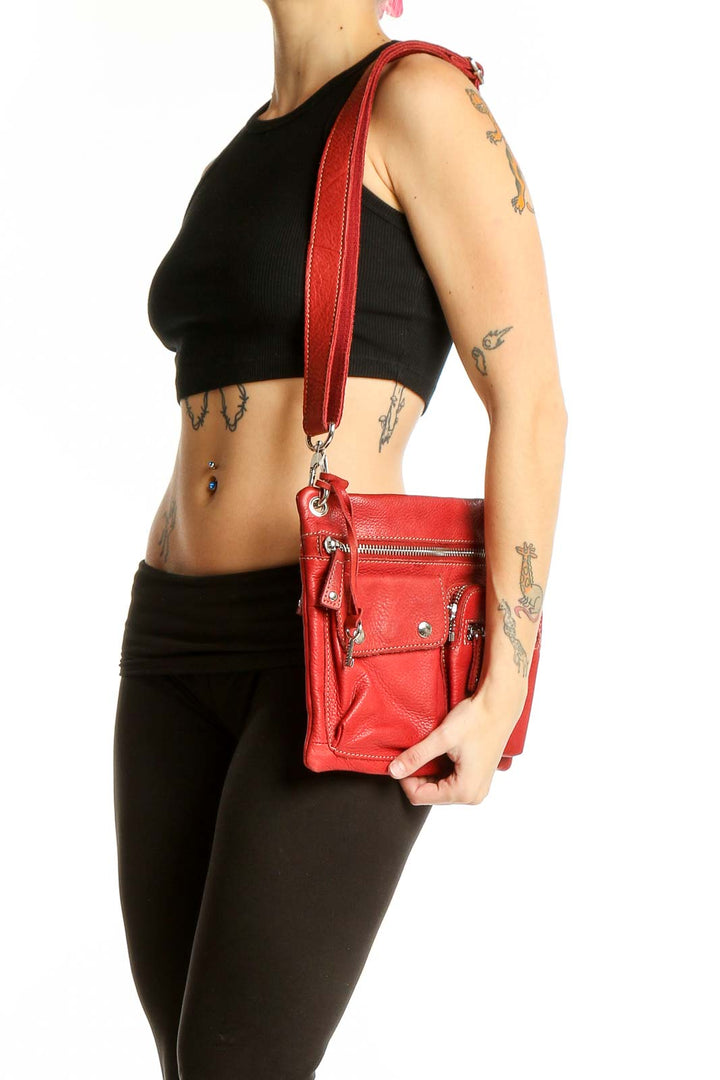 Front view of red leather Fossil crossbody bag with multiple zippered pockets