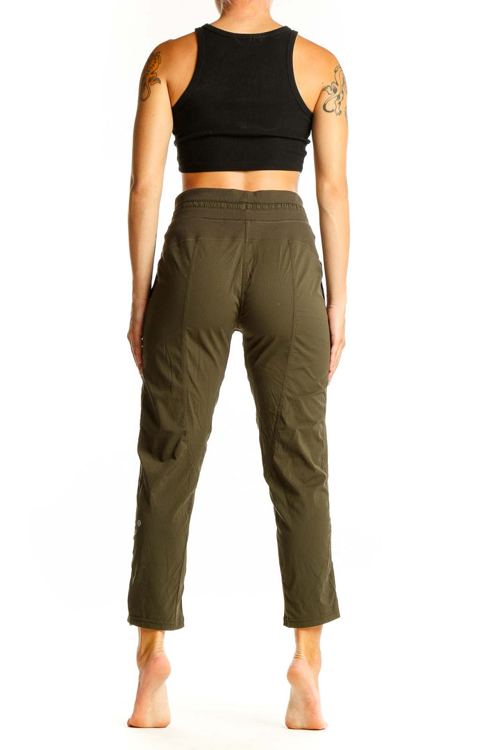 Side view of woman wearing olive green Lululemon cropped pants and black crop top