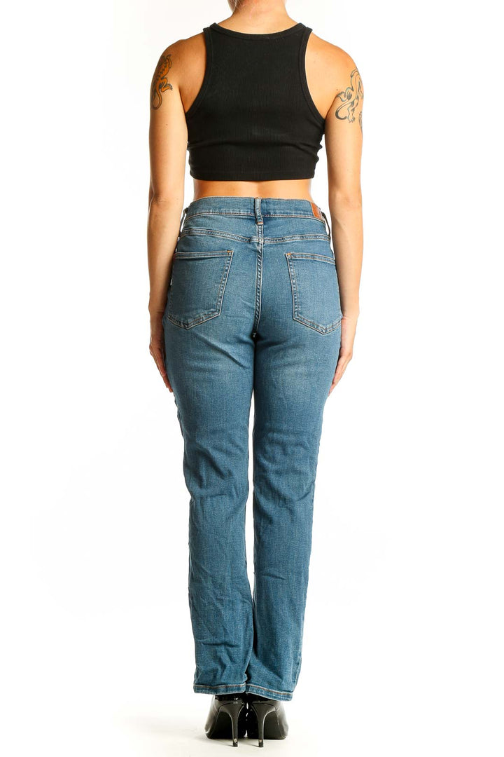 Back view of woman wearing BDG blue straight leg jeans with black crop top