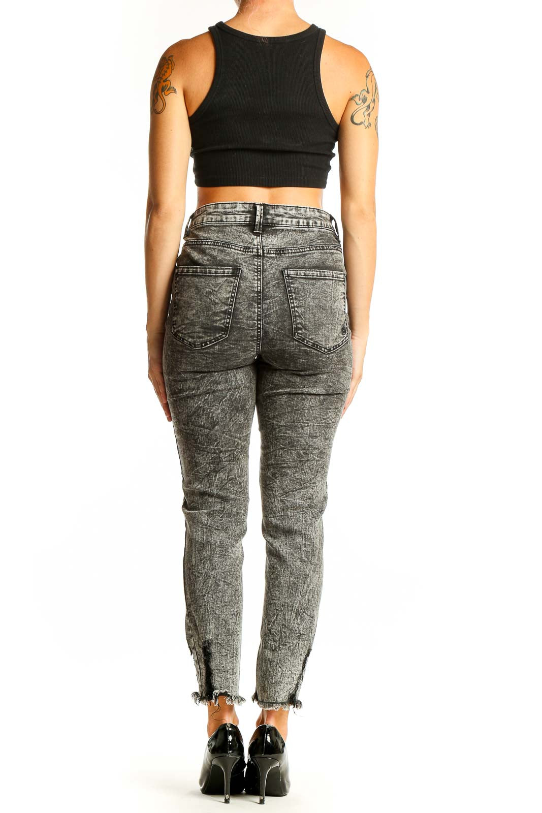 Side view of woman wearing Indigo Rein gray acid wash skinny jeans with black crop top