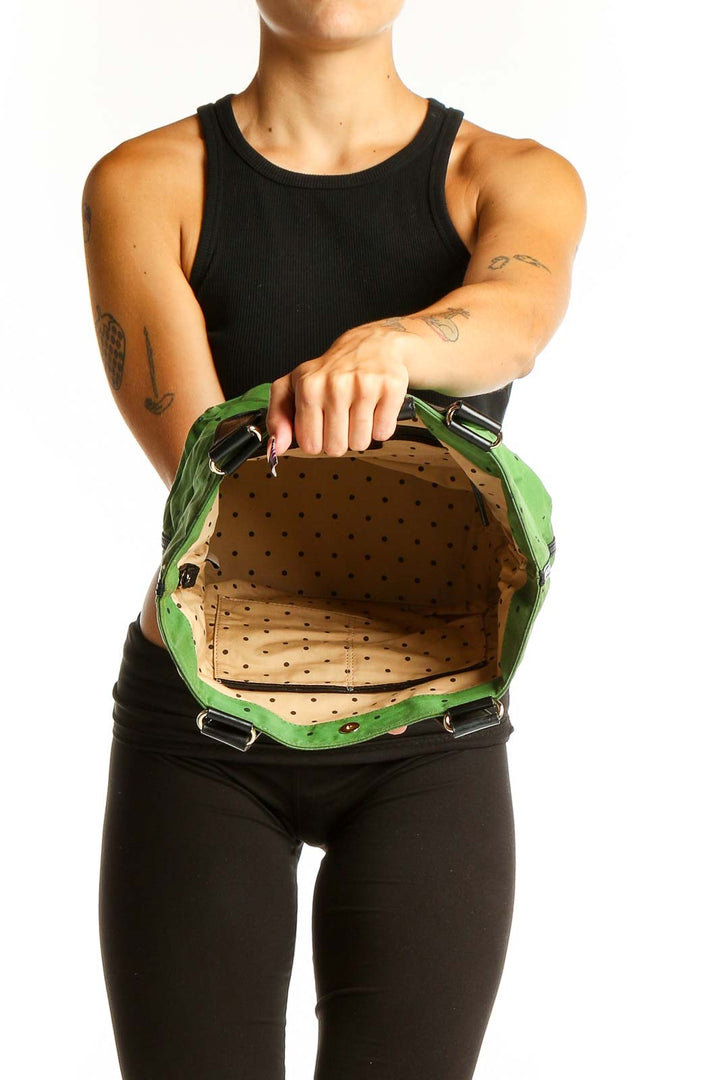Side view of Kate Spade green leather satchel held by model
