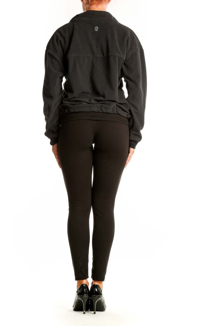 Side view of model wearing black Wrangler half-zip fleece pullover with black pants