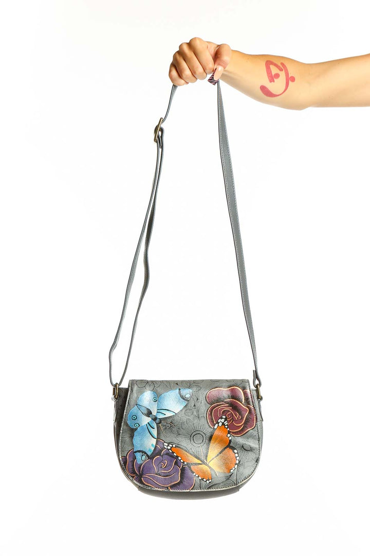 Front view of Anuschka gray leather crossbody bag with hand-painted flowers and butterflies
